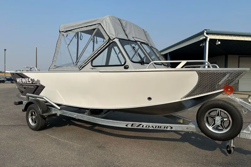 The Image of 2026 Hewescraft 180 Sportsman boat on EZ Loader trailer, parked outdoors. - 2
