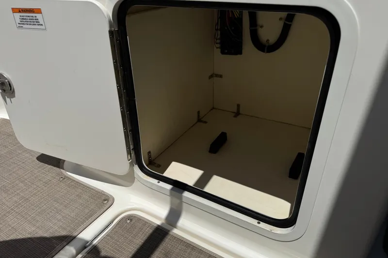 Slide: The Image of Open storage compartment on 2019 Bayliner 195 Deck Boat, showing interior space and wiring. - 31