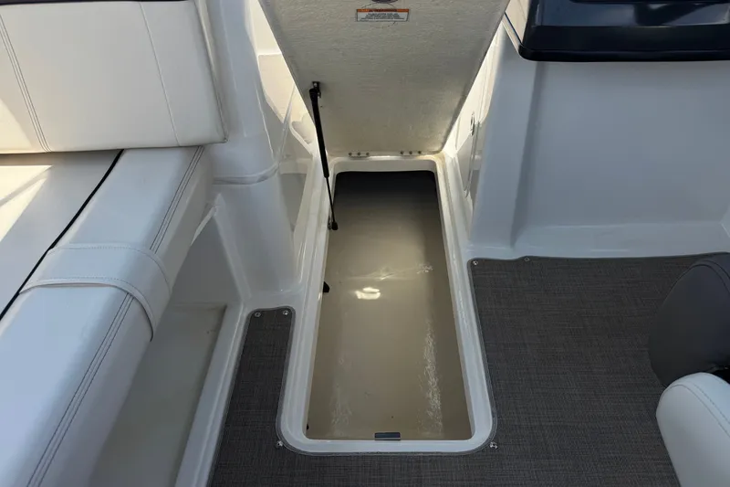 Slide: The Image of Open storage compartment on 2019 Bayliner 195 Deck Boat with white seating and gray flooring. - 29