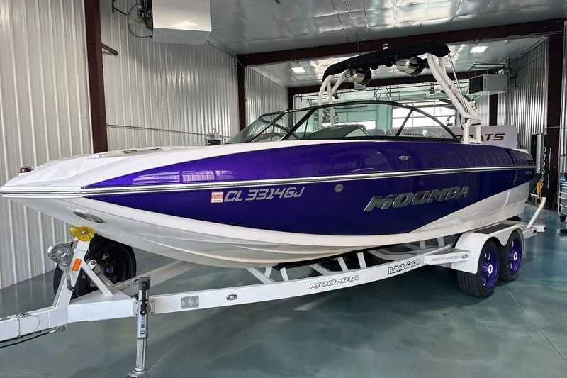 The Image of 2016 Moomba Mojo boat in a garage, featuring a sleek purple and white design. - 1