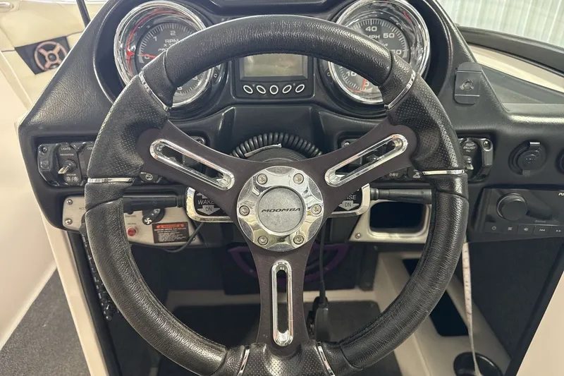 Slide: The Image of Steering wheel and dashboard of a 2016 Moomba Mojo boat, featuring gauges and controls. - 14