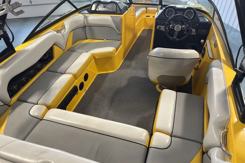 Slide: The Image of 2016 Moomba Mondo boat interior with yellow and gray seating, steering wheel, and dashboard. - 10