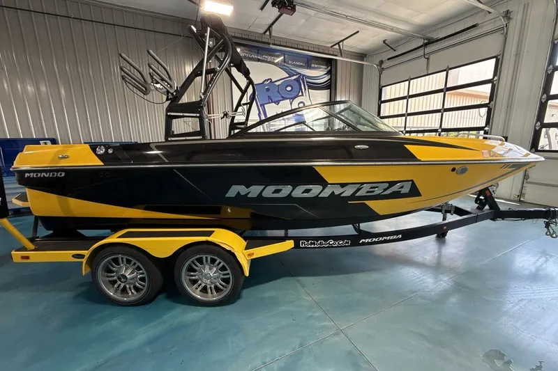 Slide: The Image of 2016 Moomba Mondo boat in black and yellow, displayed indoors on a trailer. - 6