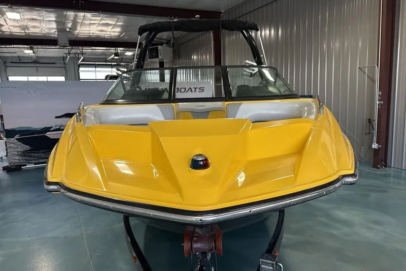 Slide: The Image of 2016 Moomba Mondo boat with a vibrant yellow hull in a showroom setting. - 8