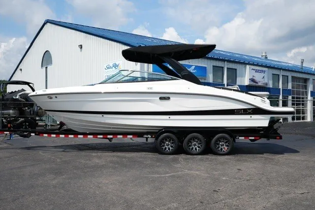The Image of 2027 Sea Ray SLX 280 boat on trailer, parked outside a marine dealership. - 1