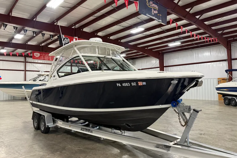 The Image of 2020 Pursuit DC 266 Dual Console boat on trailer in indoor showroom. - 0