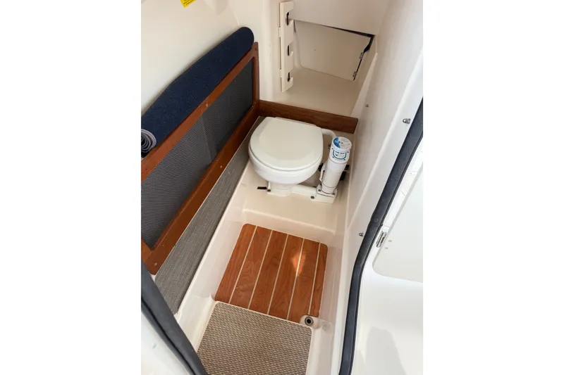 Slide: The Image of 2020 Grady-White Freedom 275 boat interior with compact marine toilet and wooden flooring. - 16