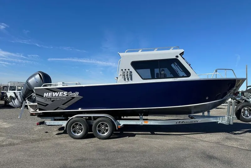 Slide: The Image of 2026 Hewescraft 240 Ocean Pro ET boat on trailer under clear blue sky. - 2