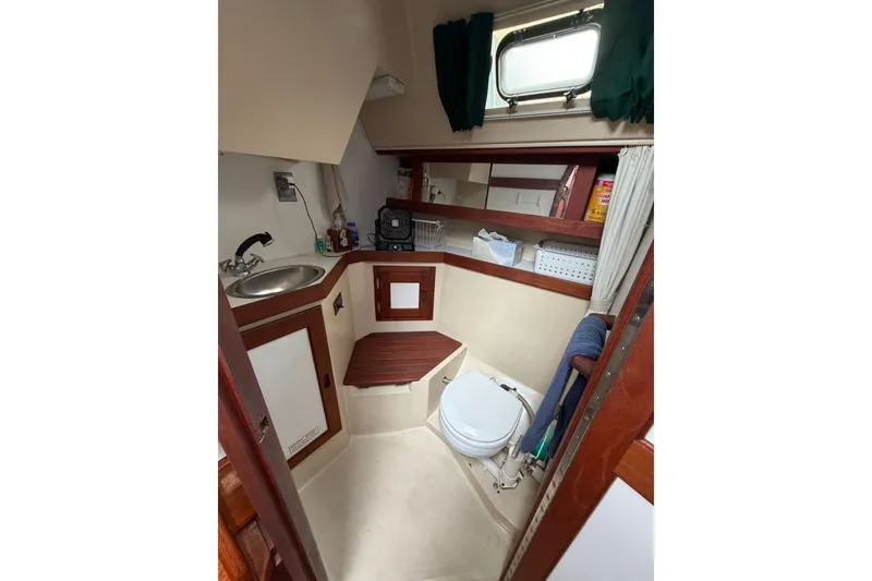 Slide: The Image of 1987 Catalina 34 sailboat bathroom with sink, toilet, and storage shelves. - 49