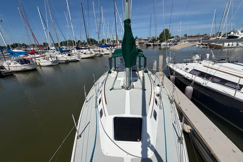Slide: The Image of 1987 Catalina 34 sailboat docked in a marina, surrounded by other sailboats. - 6