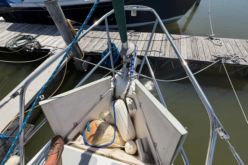 Slide: The Image of 1987 Catalina 34 sailboat bow with docked marina view, featuring ropes and fenders. - 7