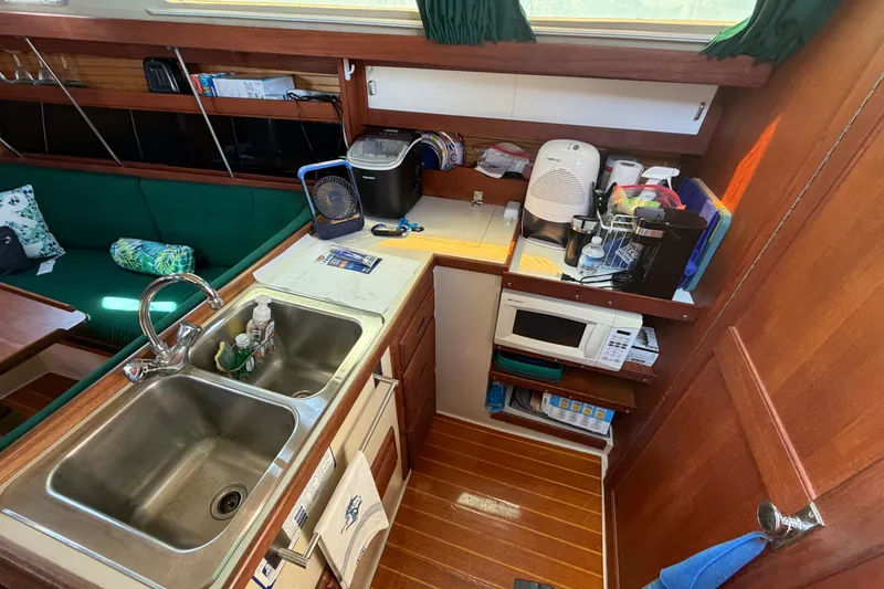 Slide: The Image of Interior of 1987 Catalina 34 sailboat galley with sink, microwave, and wooden cabinetry. - 33