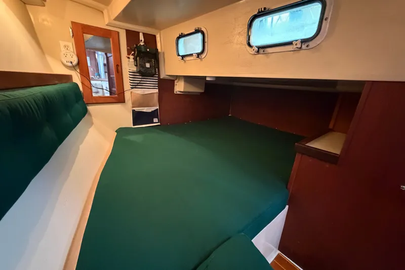 Slide: The Image of Cozy cabin interior of 1987 Catalina 34 sailboat with green bedding and wooden accents. - 30