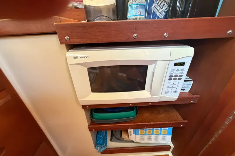 Slide: The Image of Microwave in 1987 Catalina 34 yacht kitchen with wooden shelving and storage items. - 37