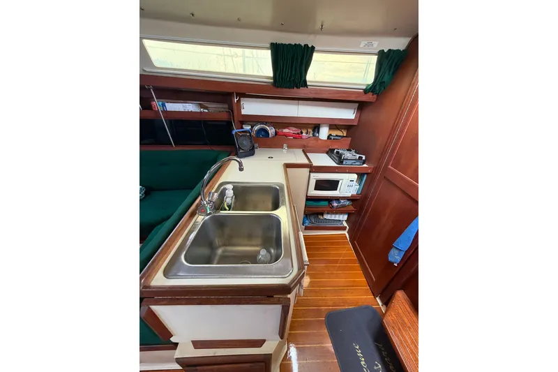 Slide: The Image of Interior of 1987 Catalina 34 sailboat kitchen with sink, microwave, and wooden cabinetry. - 35