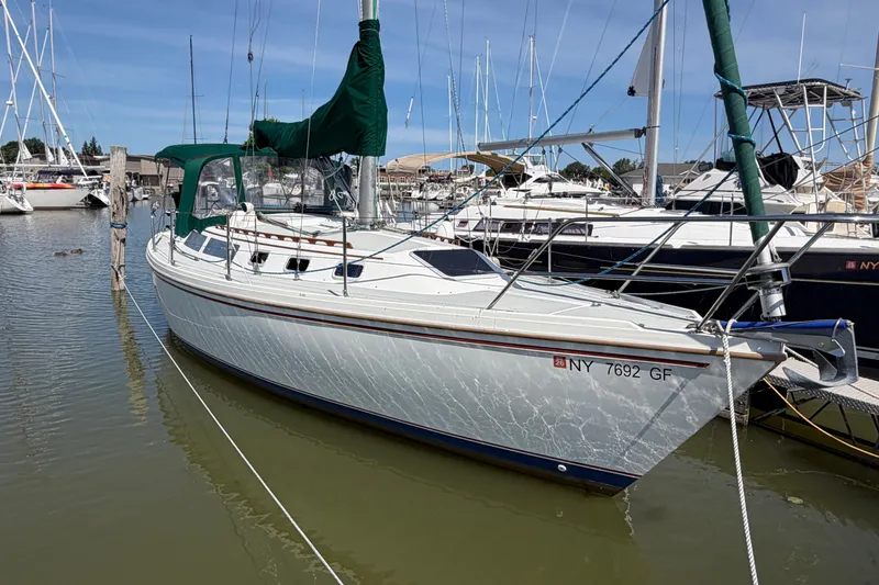 Slide: The Image of 1987 Catalina 34 sailboat docked in a marina, featuring green sail covers. - 3