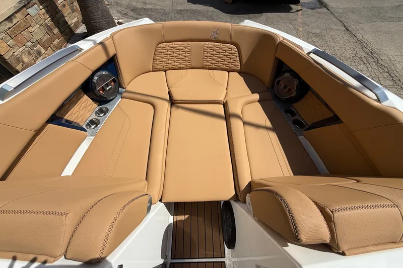 Slide: The Image of Luxurious tan seating in 2020 MasterCraft X24 boat interior, featuring cup holders and speakers. - 9