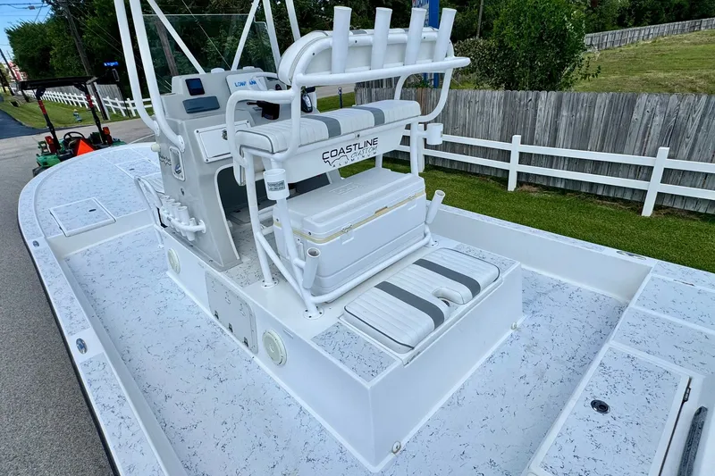 Slide: The Image of 2017 Shallow Sport 25 X3 boat with white deck and seating, parked near a wooden fence. - 8