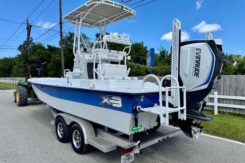 Slide: The Image of 2017 Shallow Sport 25 X3 boat on trailer with Evinrude engine, parked on street. - 2
