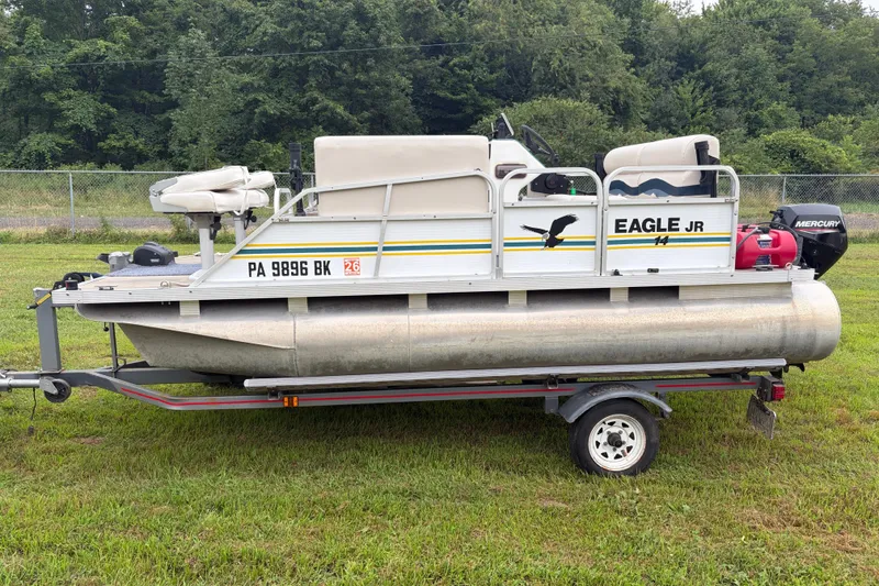 The Image of 1995 Playbuoy Eagle 14' pontoon boat on trailer, parked on grass. - 0