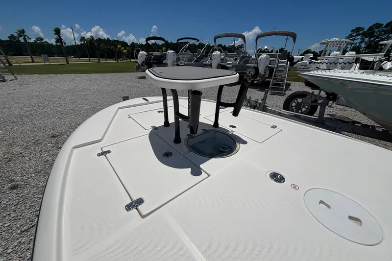 Slide: The Image of 2024 Spyder FX19 Vapor boat deck with seating, parked on gravel lot under clear sky. - 2