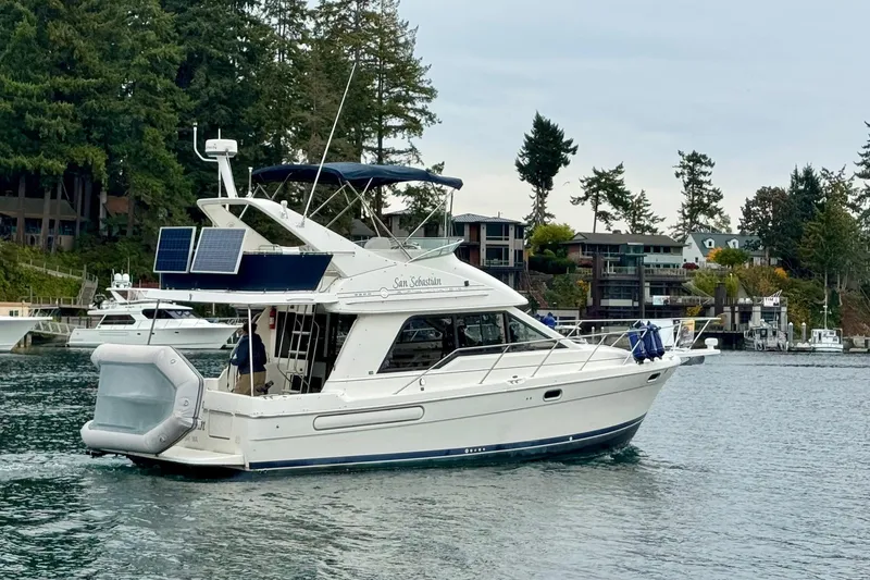 Slide: The Image of 1998 Bayliner 3388 Command Bridge Motoryacht cruising near waterfront homes and trees. - 1