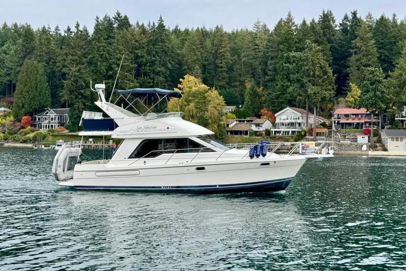 The Image of 1998 Bayliner 3388 Command Bridge Motoryacht on scenic lake with forested shoreline. - 0
