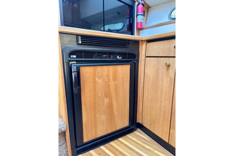 Slide: The Image of 1998 Bayliner 3388 Command Bridge Motoryacht interior with wooden cabinetry and compact refrigerator. - 26