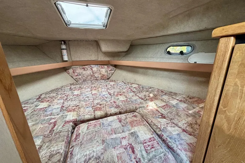 Slide: The Image of 1998 Bayliner 3388 Command Bridge Motoryacht cabin interior with patterned bedding and porthole window. - 27