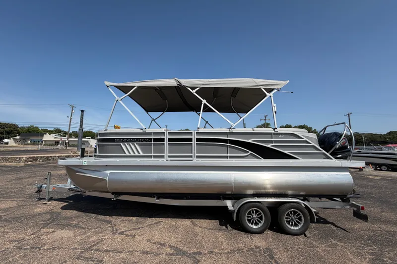 Slide: The Image of 2025 Bennington 22 L Quad Bench pontoon boat on trailer, parked outdoors. - 7