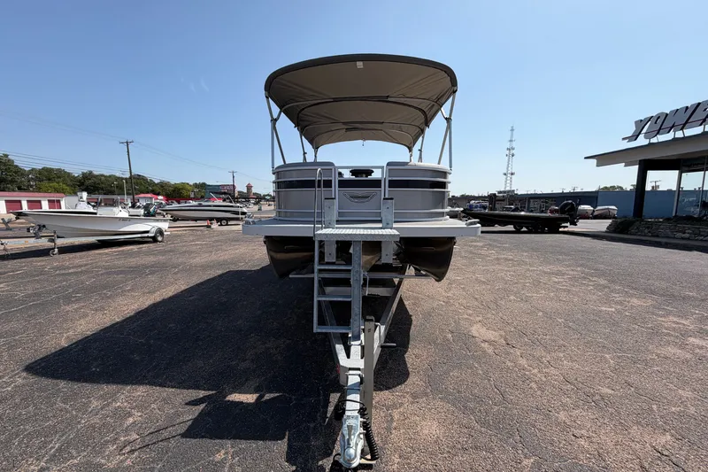 Slide: The Image of 2025 Bennington 22 L Quad Bench pontoon boat on trailer, parked outdoors. - 10