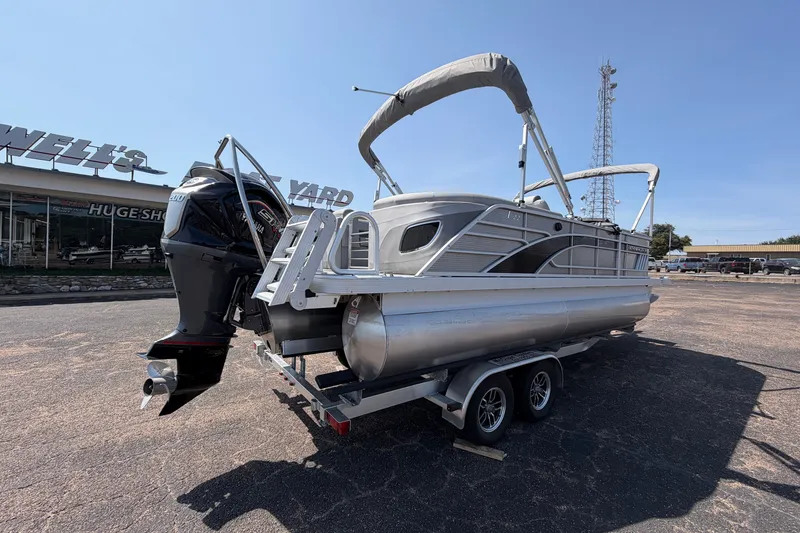 Slide: The Image of 2025 Bennington 22 L Quad Bench pontoon boat on trailer, parked outdoors. - 4