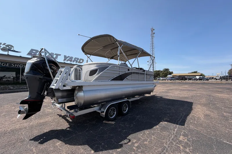 Slide: The Image of 2025 Bennington 22 L Quad Bench pontoon boat on trailer, parked outdoors. - 8