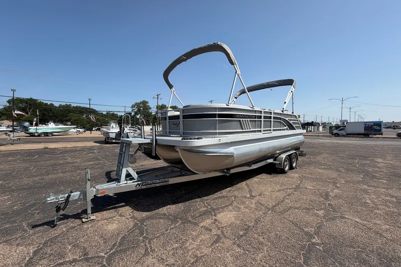 Slide: The Image of 2025 Bennington 22 L Quad Bench pontoon boat on trailer in sunny outdoor setting. - 1