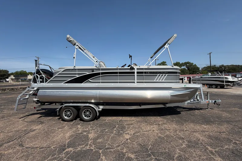 Slide: The Image of 2025 Bennington 22 L Quad Bench pontoon boat on trailer, parked outdoors. - 5