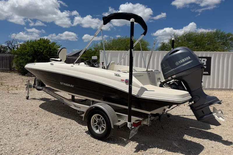 Slide: The Image of 2020 Stingray 182 SC boat with Yamaha outboard motor on a trailer, parked outdoors. - 1