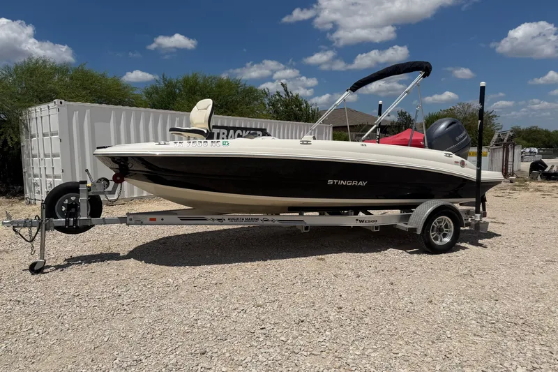 The Image of 2020 Stingray 182 SC boat on trailer, parked outdoors under a clear blue sky. - 0