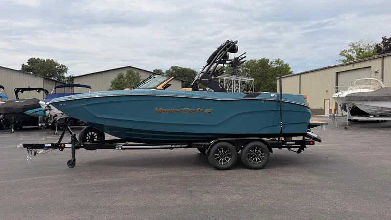 Slide: The Image of A 2027 MasterCraft XT22 boat on a trailer, in an outdoor area with other boats. - 3