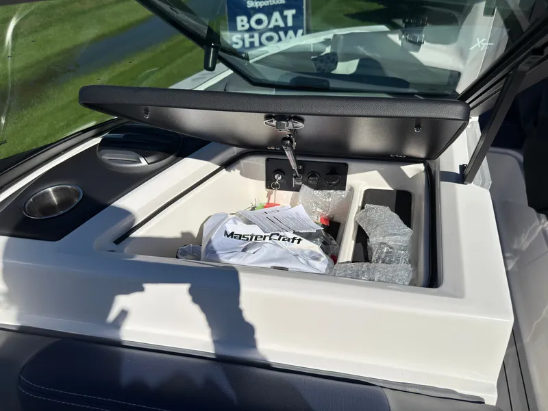 Slide: The Image of An open storage compartment on a MasterCraft XT22 boat reveals accessories and manuals. - 46