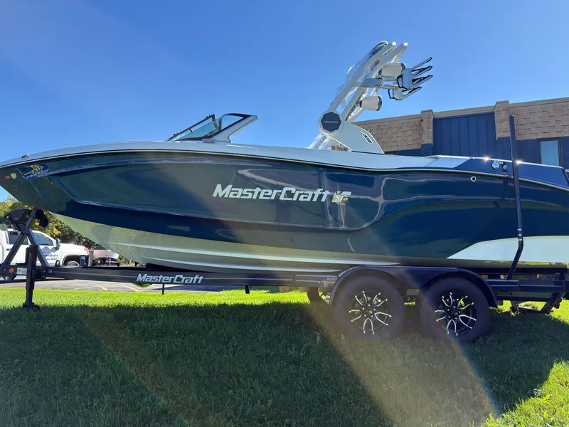 Slide: The Image of A 2027 MasterCraft XT22 boat on a trailer, set on a green lawn. - 5