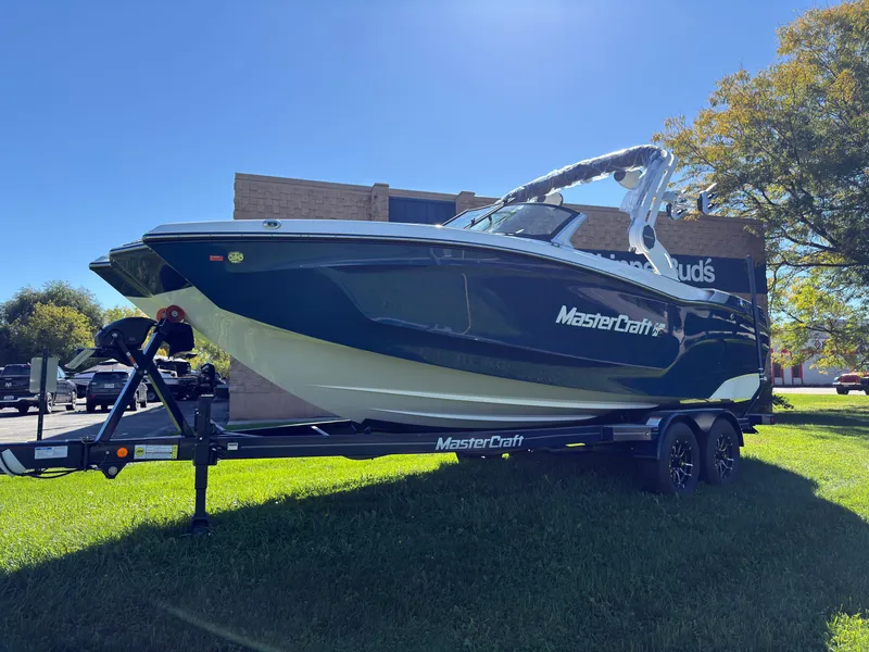 Slide: The Image of The image shows a 2027 MasterCraft XT22 boat on a trailer, surrounded by trees. - 4