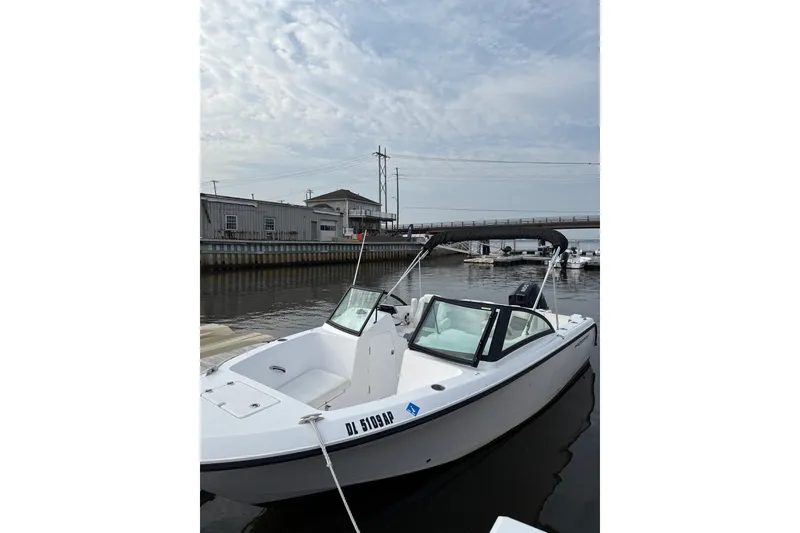 Slide: The Image of 2024 Aquasport 2200 Dual Console boat docked in a marina under a cloudy sky. - 4
