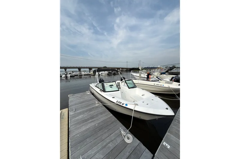 Slide: The Image of 2024 Aquasport 2200 Dual Console boat docked at marina under cloudy sky. - 3