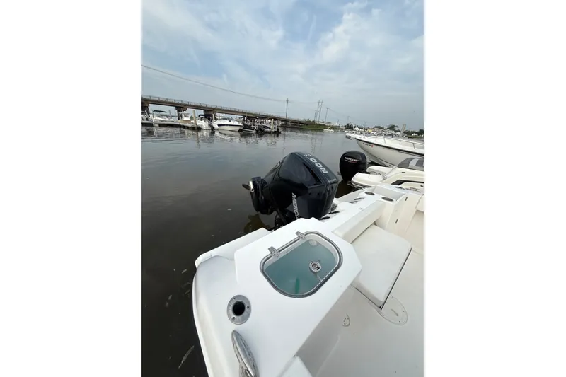 Slide: The Image of 2024 Aquasport 2200 Dual Console boat docked with outboard motor, under cloudy sky. - 9