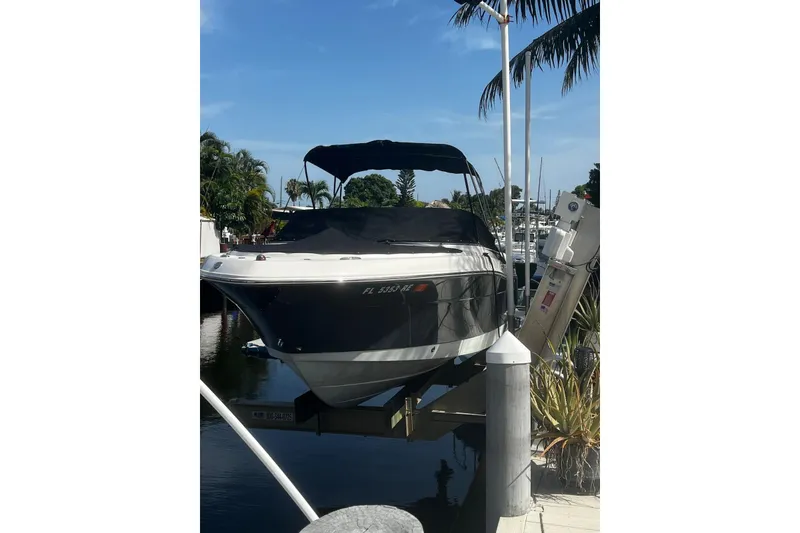 Slide: The Image of 2016 Robalo R227 Dual Console boat docked with cover, surrounded by palm trees. - 17
