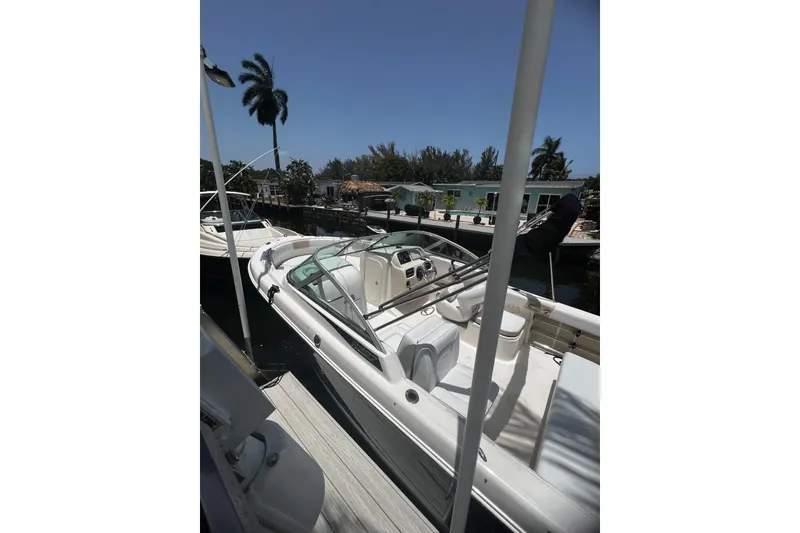 Slide: The Image of 2016 Robalo R227 Dual Console boat docked near palm trees and waterfront homes. - 3