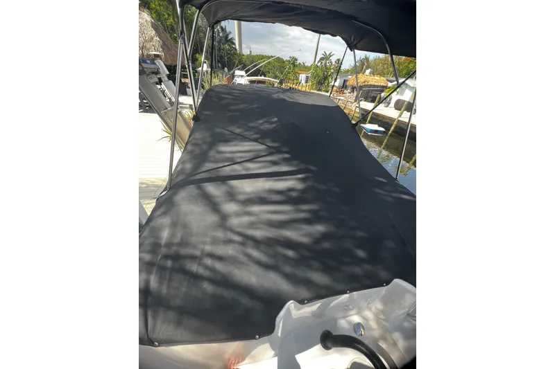 Slide: The Image of 2016 Robalo R227 Dual Console boat with black cover docked by a canal. - 13