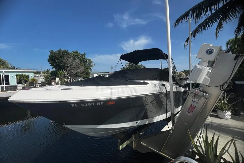 Slide: The Image of 2016 Robalo R227 Dual Console boat docked, covered, with palm trees and blue sky background. - 1