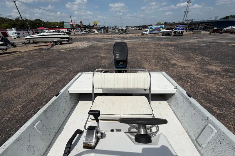 Slide: The Image of 2004 Kenner 180VX Tunnel boat with steering wheel and seating, parked on a lot under a cloudy sky. - 18