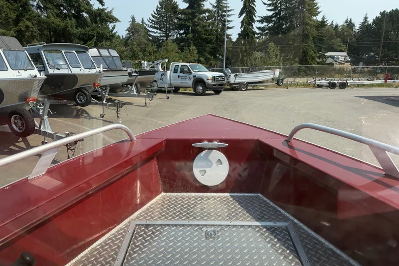 Slide: The Image of 2024 Hewescraft 210 Sea Runner ET boat at dealership, surrounded by trailers and trees. - 8